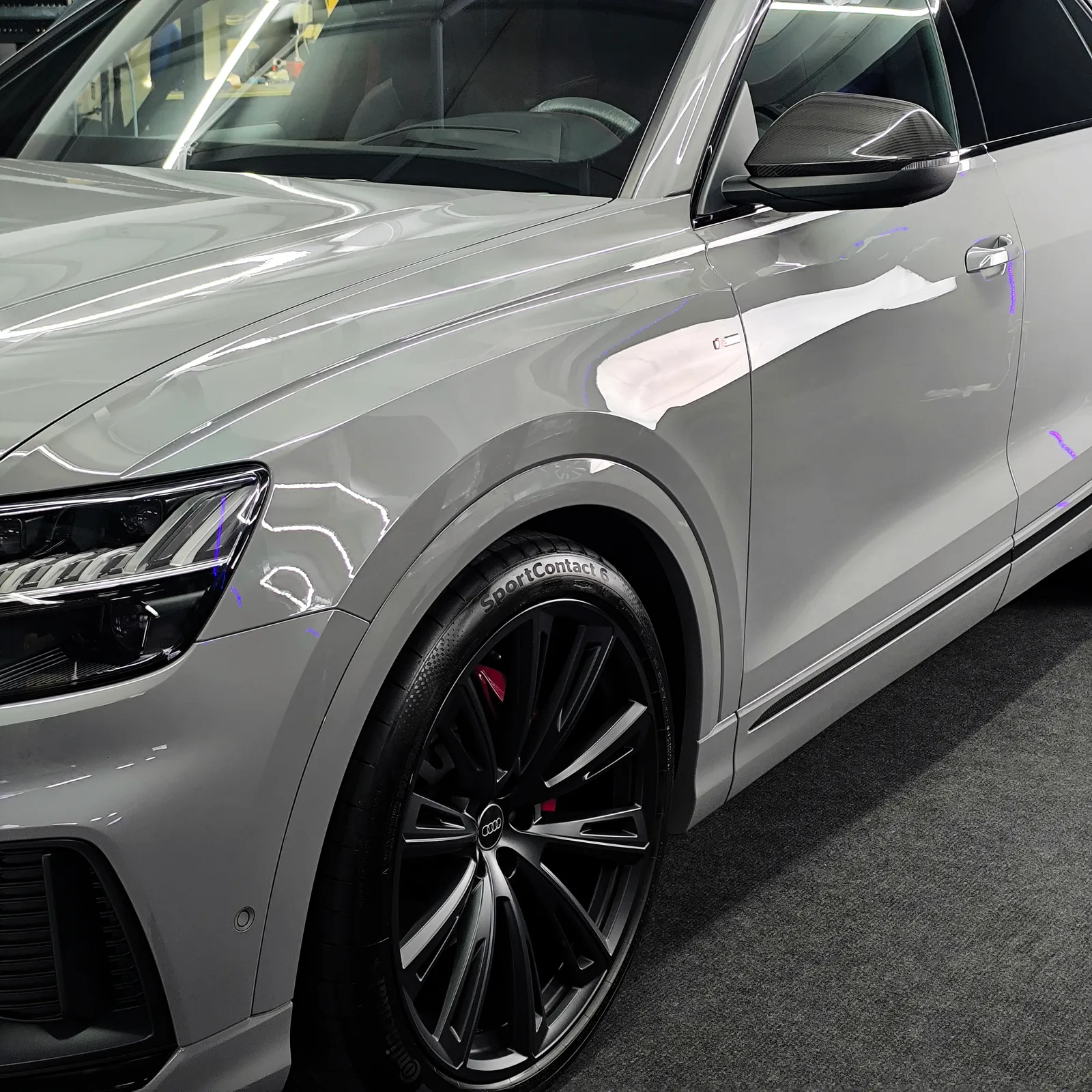Grauer Audi Q8 von der Seite mit frisch poliertem Lack und roten Bremssätteln