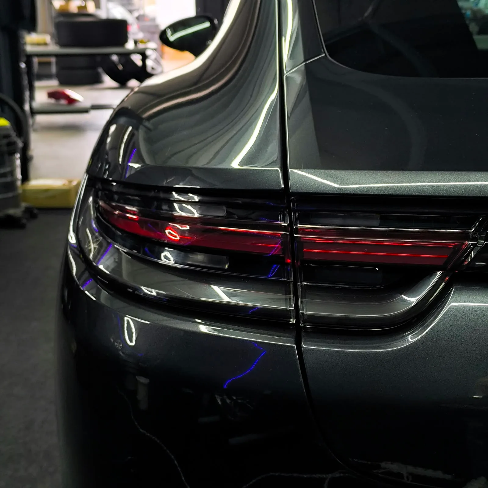 Heckleuchte eines dunklen Porsche Macan, nass nach der letzten Politur