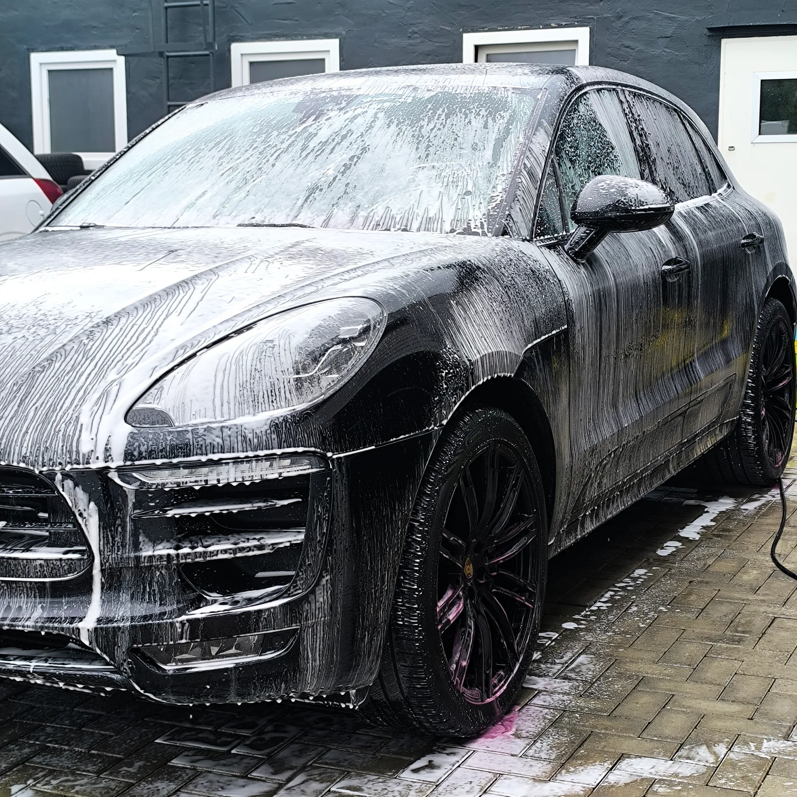 Schwarzer Porsche Macan komplett mit Reinigungsschaum bedeckt