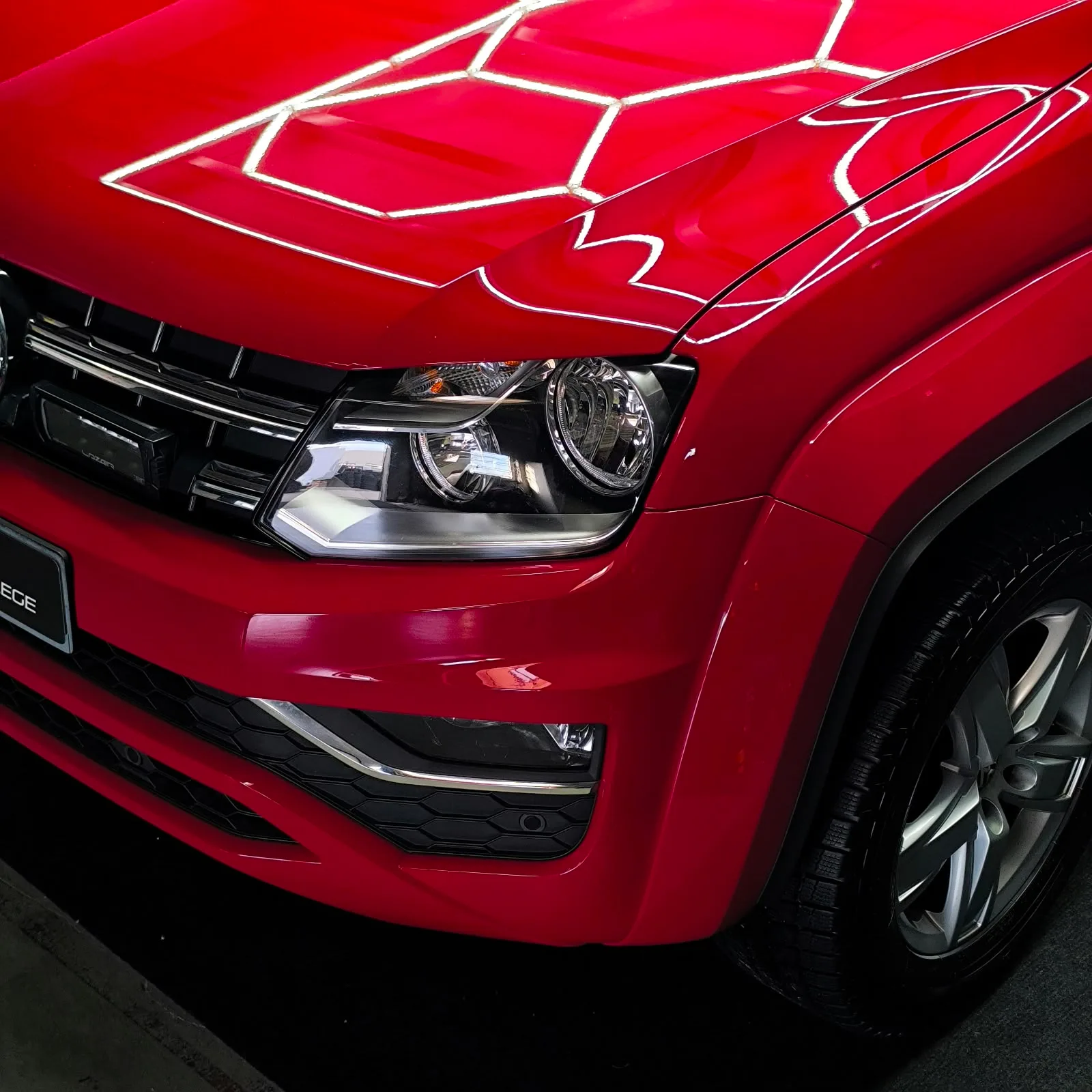 Frontpartie eines roten VW Amarok mit Deckenlicht-Spiegelung im Lack